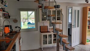 Une cuisine avec une fenêtre, un évier et un escalier menant à une porte.