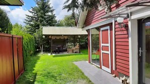 A red house with a covered patio, a lawn, and a sliding glass door. - Lychenlodge on Oberpfuhl Lake with canoe & fireplace (Lychen)