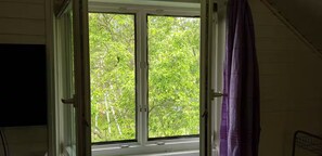 Une pièce avec une fenêtre, un rideau violet et un lit.