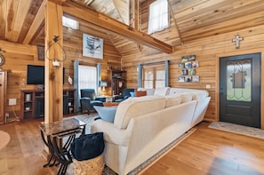 Un intérieur en bois avec un canapé, une table à manger et une croix au mur.