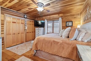 A bedroom with a wooden ceiling, a bed with a beige bedspread, a ceiling fan, a TV, and a window with blinds. - The Lodge @ Lake Cumberland  
For Families and Friends! (Jamestown)