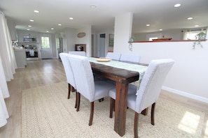 A dining area with a wooden table, grey upholstered chairs, and a woven rug. - Newly Renovated Marshview Retreat in the Heart of Wellfleet (2440) (Wellfleet)