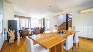 Ein modernes Wohnzimmer mit einem Holzesstisch, weißen Stühlen, einer Couch und einer Treppe.