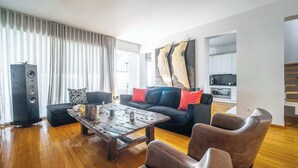 Ein modernes Wohnzimmer mit Couch aus Leder, Holz-Couchtisch und einem großen Lautsprecher.