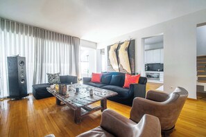 A modern living room with a wooden coffee table, leather sofa, and a large speaker. - K&K Villa in Athens Riviera with private pool (Voula)