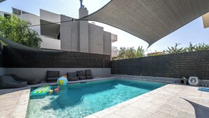 Ein Swimmingpool mit Sonnenschirm, Liegestühlen und einem kleinen Schlauchboot.