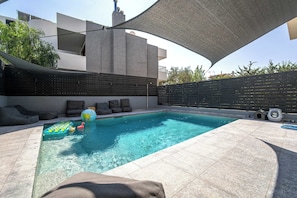 A swimming pool with a sunshade, lounge chairs, and a small inflatable boat. - K&K Villa in Athens Riviera with private pool (Voula)