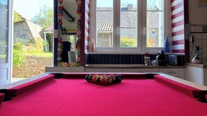 A pool table with a red felt surface and a single white cue ball in the center. - Le Maguero (Guégon)
