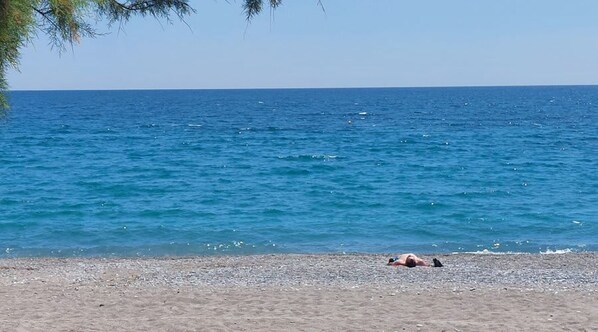 A beach with a person lying on the sand, a clear sky, and the sea. - Urban Panorama - Stylish Stay in Kalamata (Kalamata)