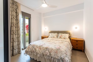 A bedroom with a bed, a ceiling fan, a nightstand, and a sliding glass door. - Urban Panorama - Stylish Stay in Kalamata (Kalamata)