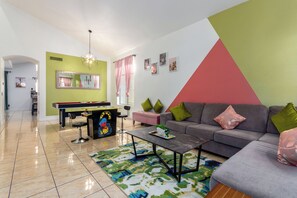 A living room with a sofa, coffee table, and a piano. - Cactus House: 5BR Family Fun Hub (Avondale)