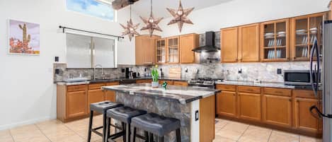 Una cocina moderna con una isla grande, armarios de madera y salpicadero de piedra.