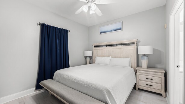 Camera da letto con un letto, comodini, una ventola a soffitto, una panca e vista sull'esterno.