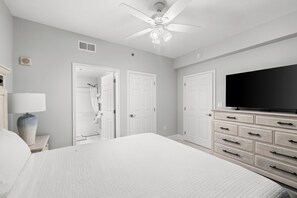 A bedroom with a bed, a TV, a dresser, and a ceiling fan. - Laketown Luxury| Unit 935| Fully Renovated (Panama City Beach)