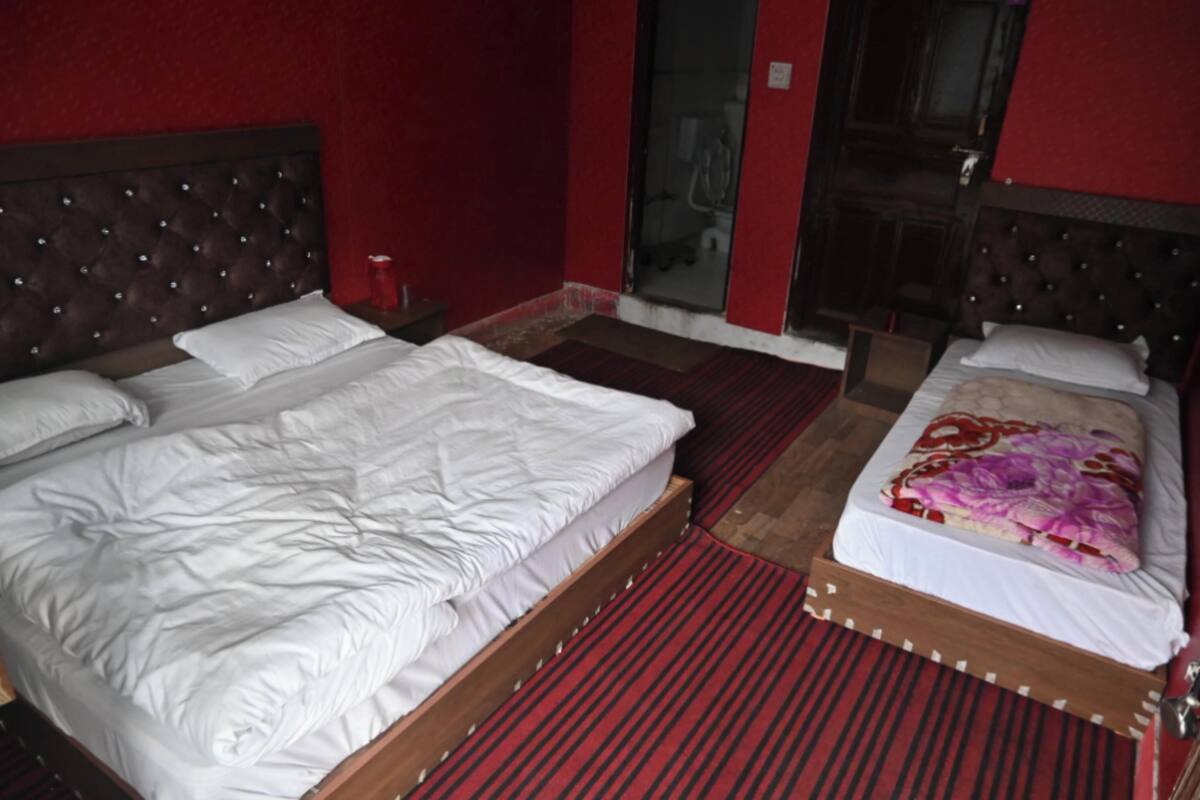 A hotel room with two beds, a red carpet, and a red wall.