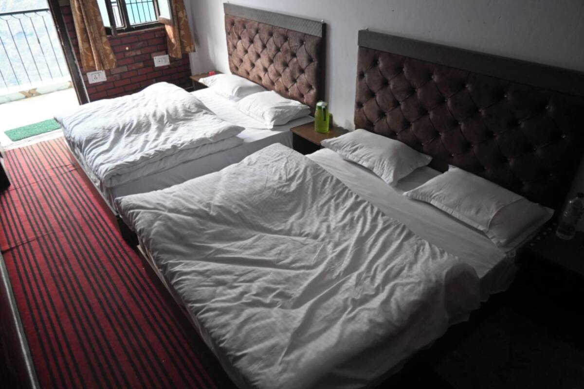 A hotel room with two beds, a red-striped carpet, and a brick wall.