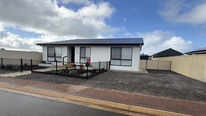 A single-story building with a flat roof, a fenced yard, and a gravel driveway.