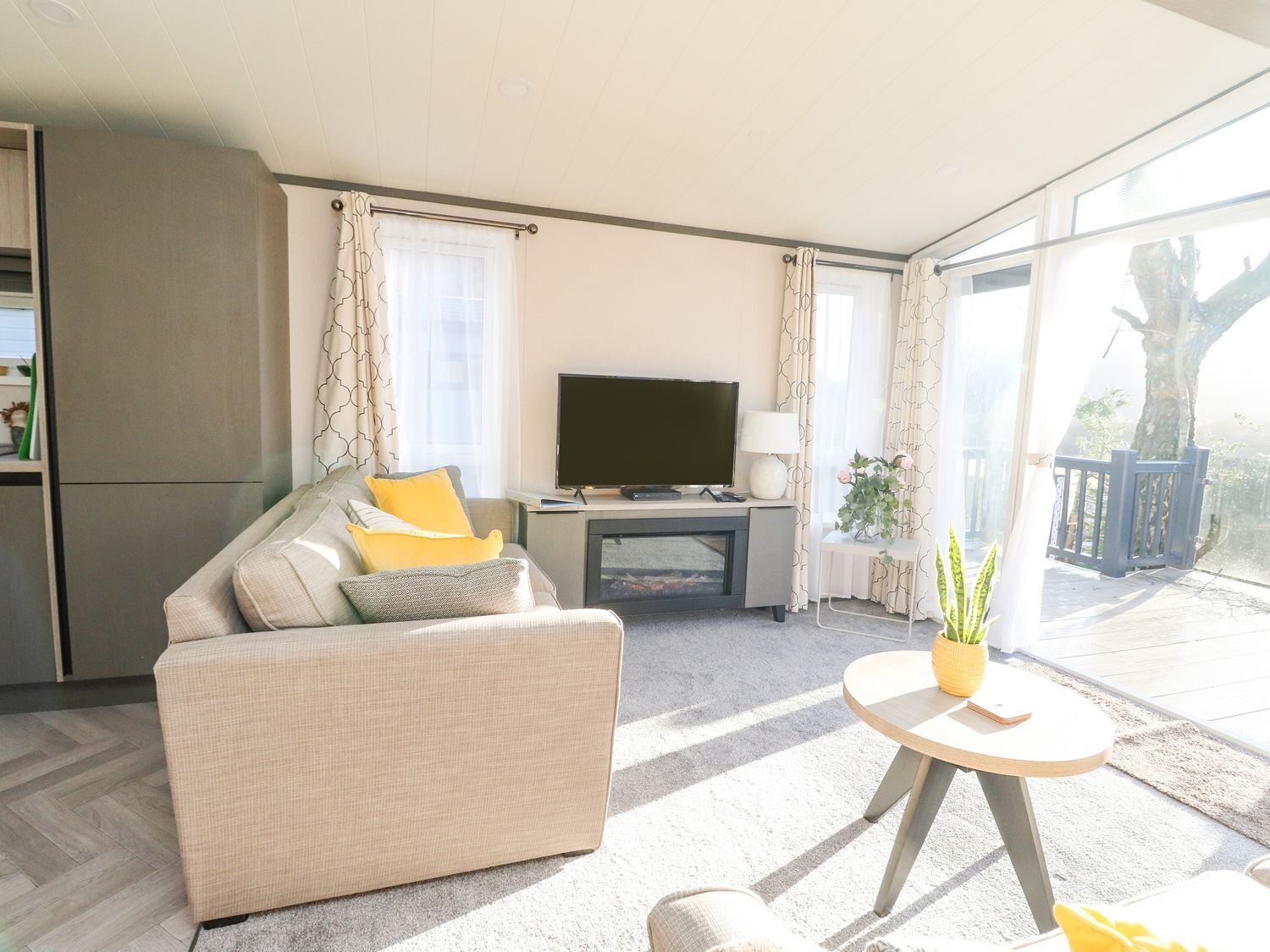 A living room with a sofa, TV, and a small table with a plant.