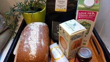 Un plateau contenant un pain, une plante, un paquet de café, un carton de lait, un pot de confiture et un paquet de beurre.