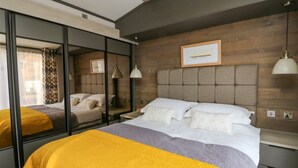 A modern hotel room with a large bed, a mirror, and a framed picture on the wall.