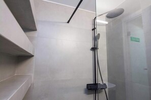 Eine moderne Dusche mit Glastrennwand, Duschbrausehandstück und einer fest installierten Bedienkonsole.