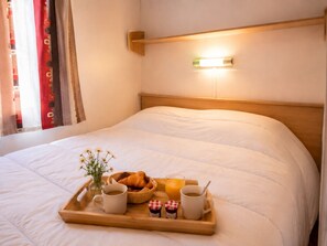A neatly made bed with a tray of breakfast items including croissants, juice, coffee, and jam.