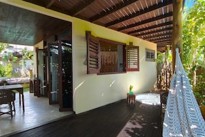 Un espacio al aire libre techado con una terraza de madera, un jacuzzi y una hamaca.