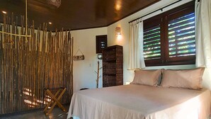 Un dormitorio con cama, pared de madera, cesta y ventana con persianas.