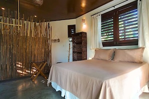 Un dormitorio con cama, pared de madera, cesta y ventana con persianas.