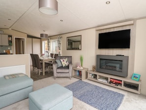 A living room with a television, sofa, ottoman, and a dining area with a table and chairs.