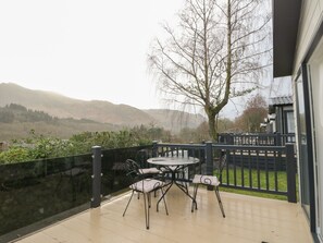 A balcony with a table and chairs, a view of hills, and a tree. - Rowan (Crieff)