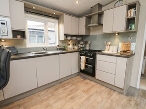 A modern kitchen with a built-in oven, a stove, and a window. - Rowan (Crieff)