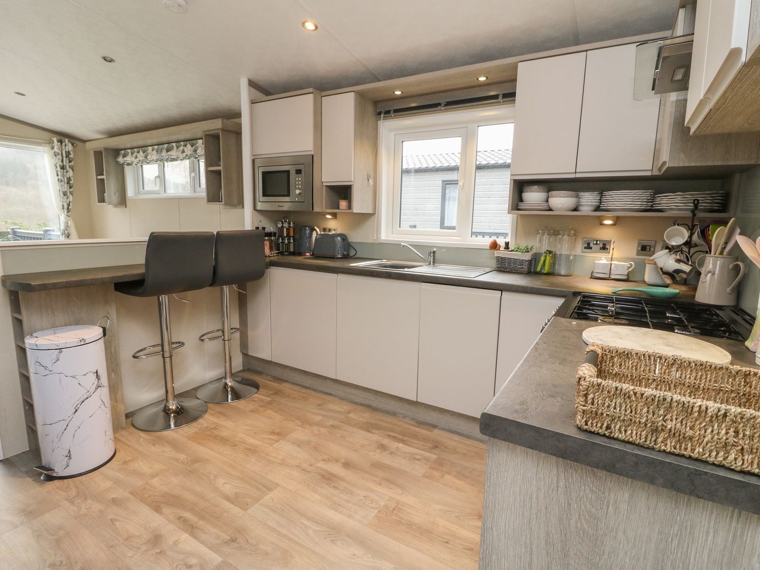 Una cucina moderna con angolo bar, pavimento in legno e una finestra che lascia entrare luce naturale.