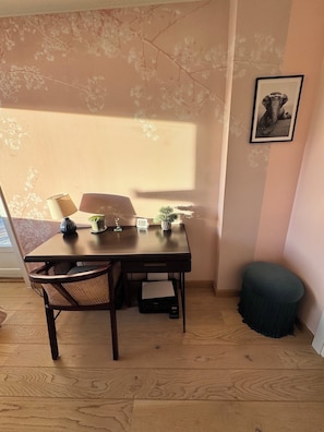 Un coin repas comprenant une table, des chaises, une petite plante, une horloge et un tableau encadré accroché au mur.