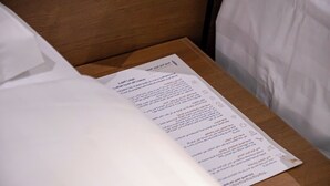 A hotel room with a wooden headboard, a white bedspread, and a menu on the nightstand. - Rayan Al Jiwar Hotel (Makkah)