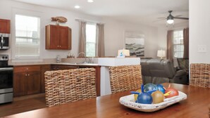 Una cucina con mobili in legno, un tavolo da pranzo con sedie in vimini e una ventola a soffitto.