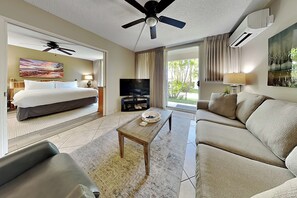 Ein Hotelzimmer mit Bett, Fernseher, Couchtisch, Sofa und Deckenventilator.