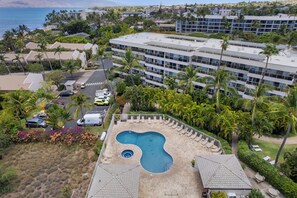 A hotel with a swimming pool, multiple floors, and a view of the ocean. - Maui Banyan G-105 | Lush Oasis + Steps to Beach! (Kihei)