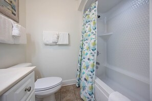 A bathroom with a toilet, a sink, a bathtub, and a shower curtain. - Phoenix Ix 607 2 Bedroom Condo (Orange Beach)