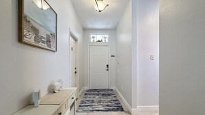 A hallway with a light-colored wall, a framed picture, a white door, and a blue and white striped rug. - Whispering Palms - Luxury 4-Bedroom Pool Home Near 4 Villa (Kissimmee)