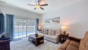 A living room with a ceiling fan, a sofa, a coffee table, and a lamp. - Whispering Palms - Luxury 4-Bedroom Pool Home Near 4 Villa (Kissimmee)