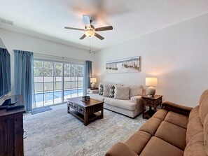 Ein Wohnzimmer mit Deckenventilator, einer Couch, einem Couchtisch und einer Lampe.