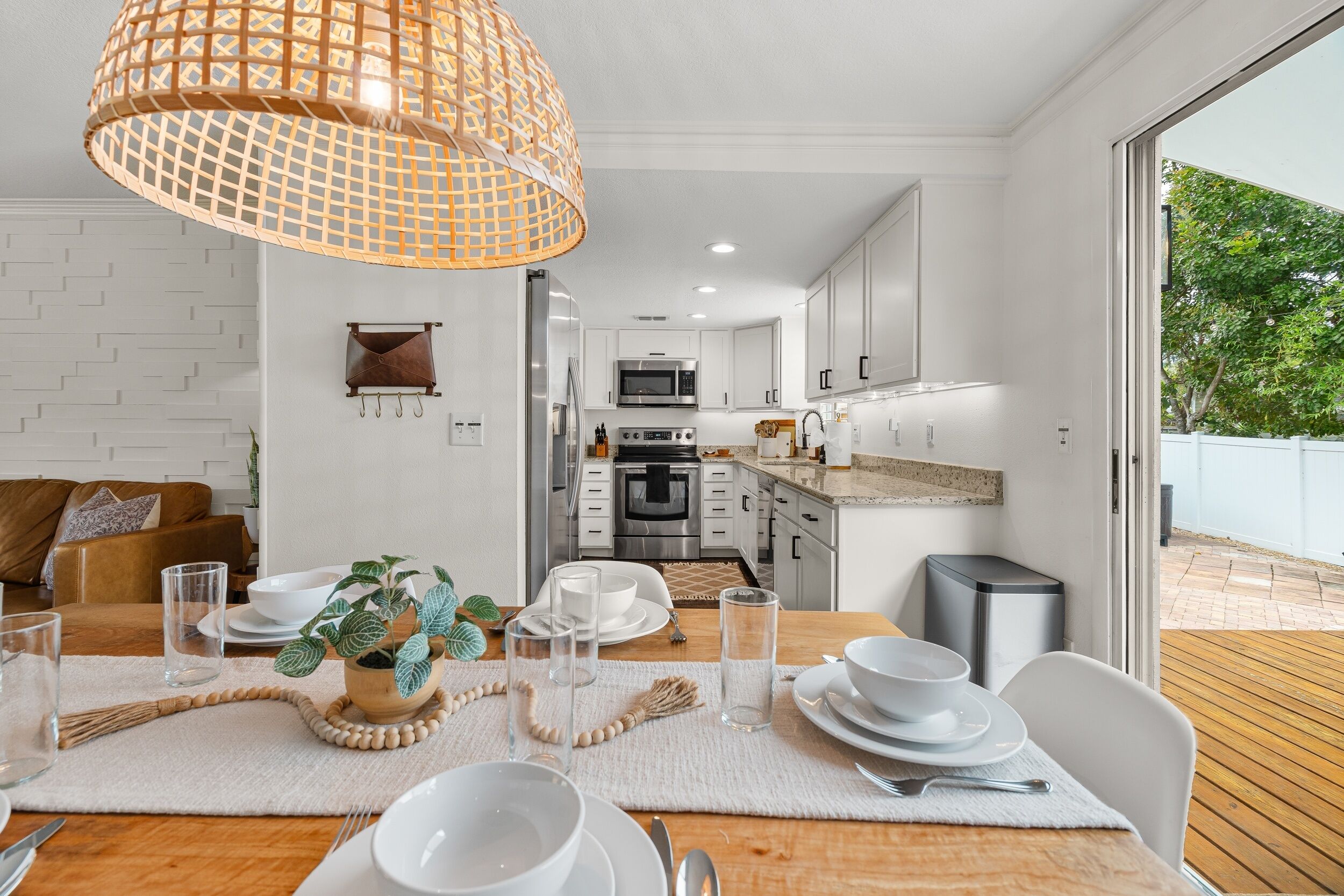 A modern kitchen with white cabinets, stainless steel appliances, and a dining area with a wooden table set for a meal.