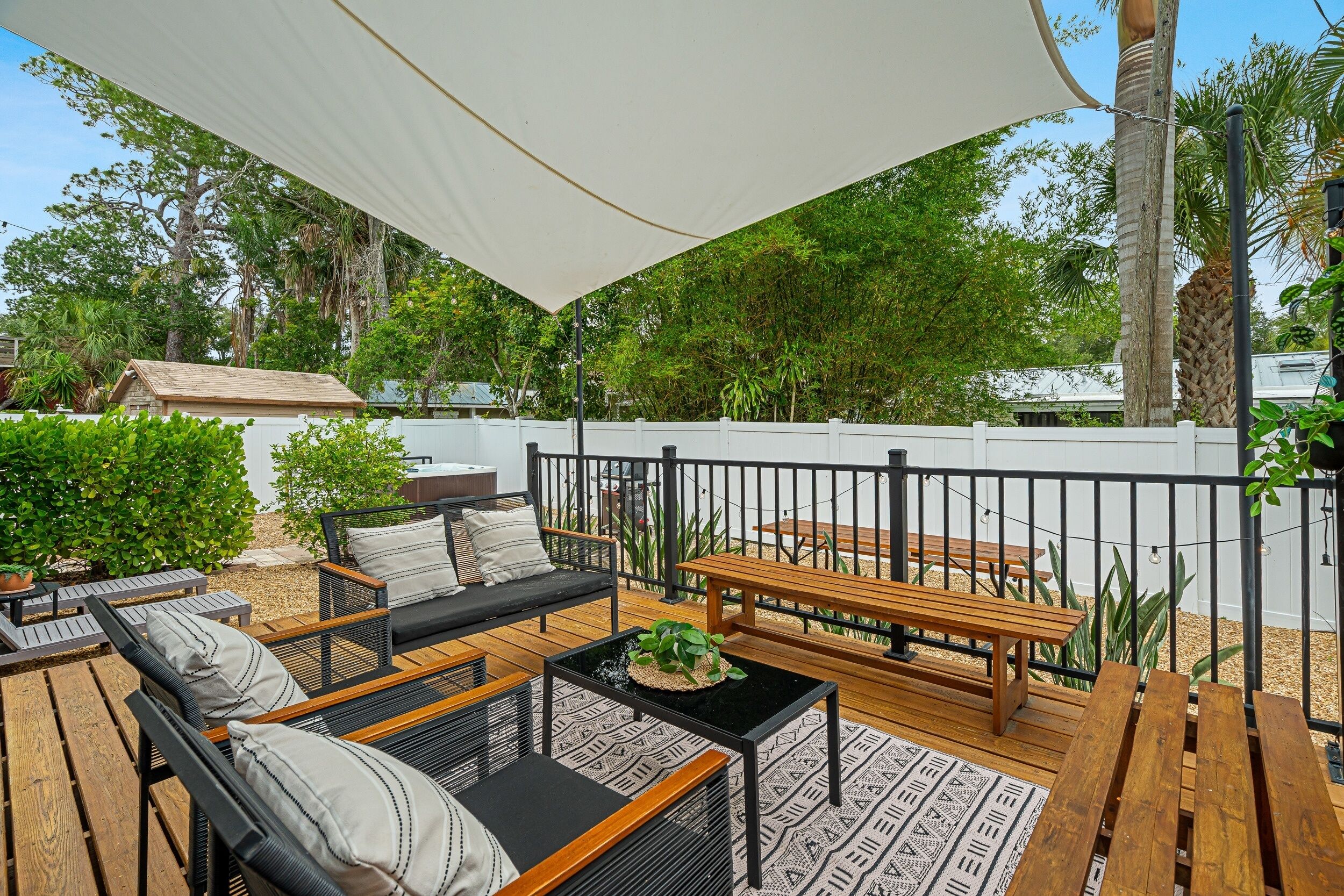 A deck with outdoor furniture, a table with a plant, and a white canopy.