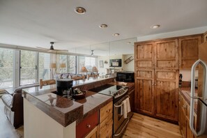 Eine moderne Küche mit einer großen Kochinsel, Holzschränken, einer Mikrowelle und einem Kühlschrank.