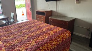 A hotel room with a bed, a TV mounted on the wall, a desk, and a chair. - Regency Inn (Riverdale)