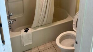 A bathroom with a shower, bathtub, toilet, and a towel rack. - Regency Inn (Riverdale)