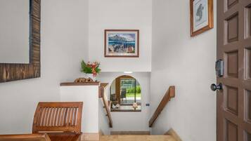 Una escalera conduce a un rellano con un cuadro enmarcado, un banco de madera y una puerta.