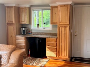 A compact kitchen with wooden cabinets, a coffee maker, and a dishwasher.