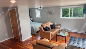 Uma sala de estar com sofá, mesa de centro e janela com vista para árvores.